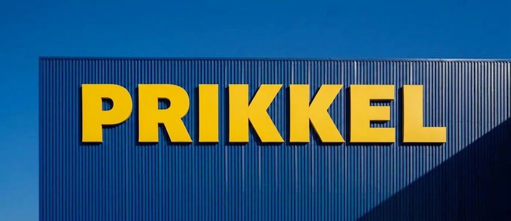 Gele PRIKKEL-letters op een blauwe golfplaten gevel tegen een blauwe lucht